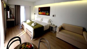 A hotel room with a bed, a sofa, a desk, and a fruit bowl. - Aura Boutique Hotel (Kefalonia)