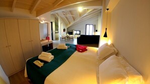 A bedroom with a bed, a desk, and a chair in the background. - Aura Boutique Hotel (Kefalonia)