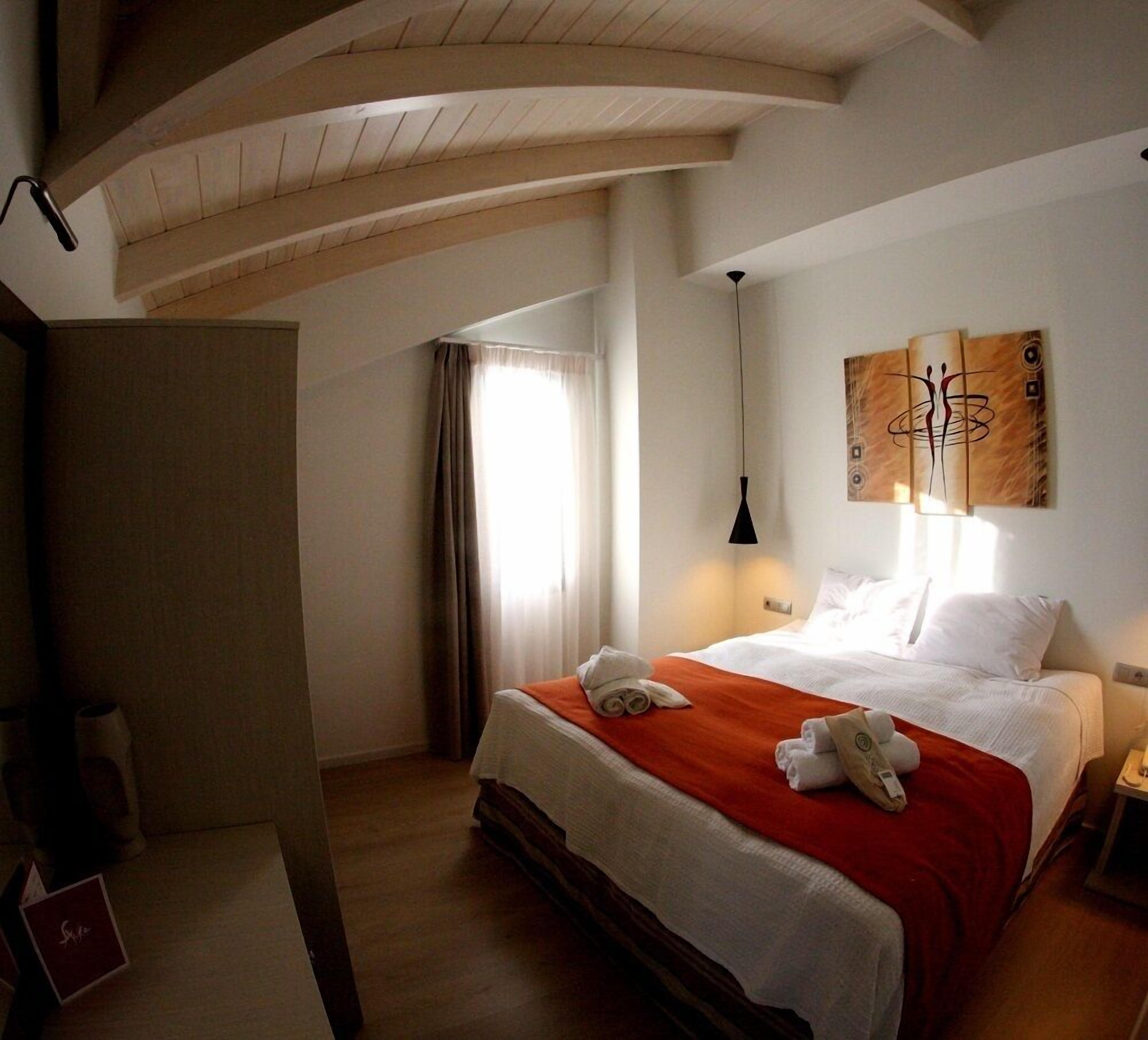 A hotel room with a bed, a nightstand, a lamp, and a painting on the wall.