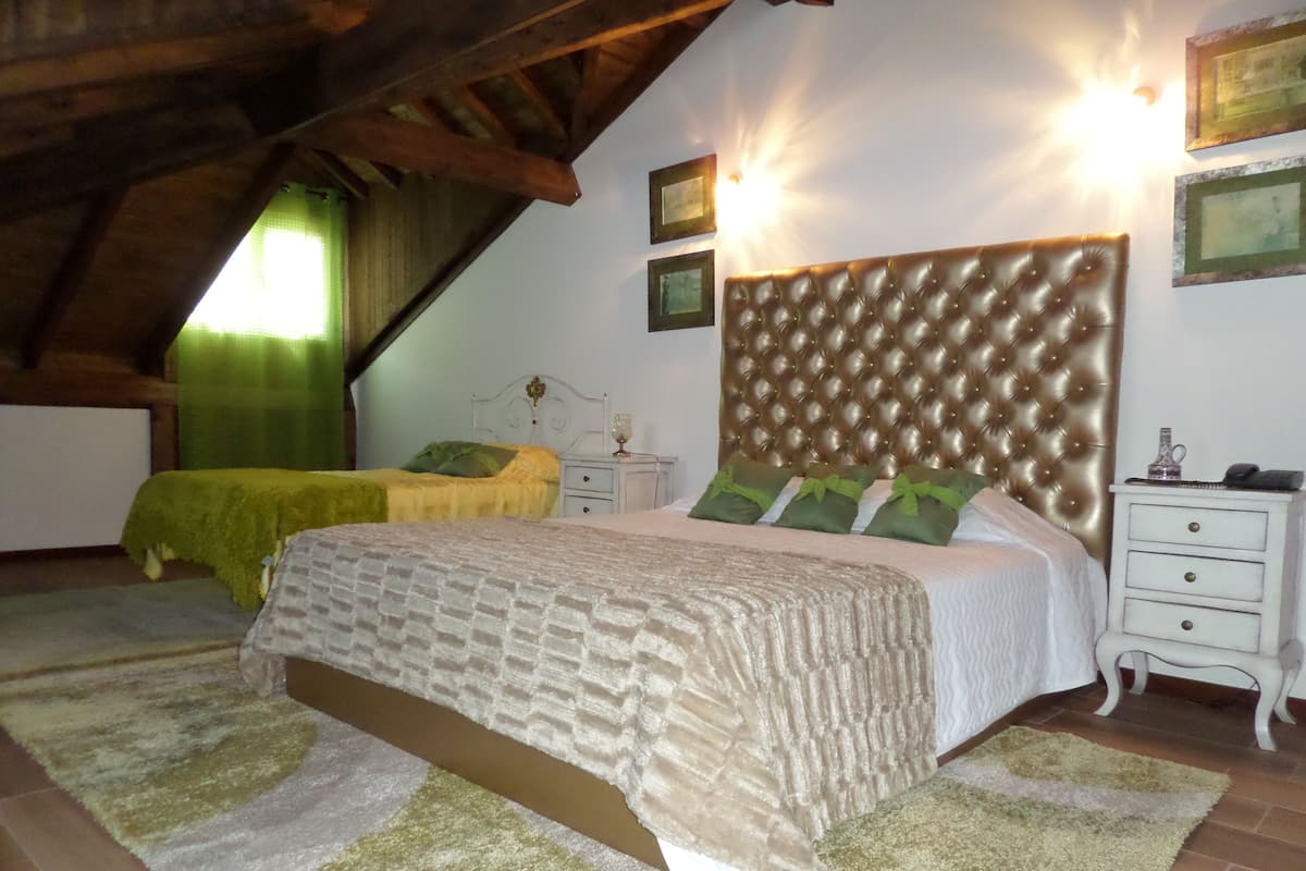 A bedroom with a large bed, two bedside tables, a nightstand, and a headboard.