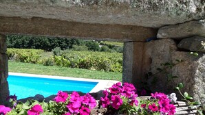 A stone archway framing a pool with vibrant pink flowers in the foreground. - Casa Grande do Seixo (Chaves)