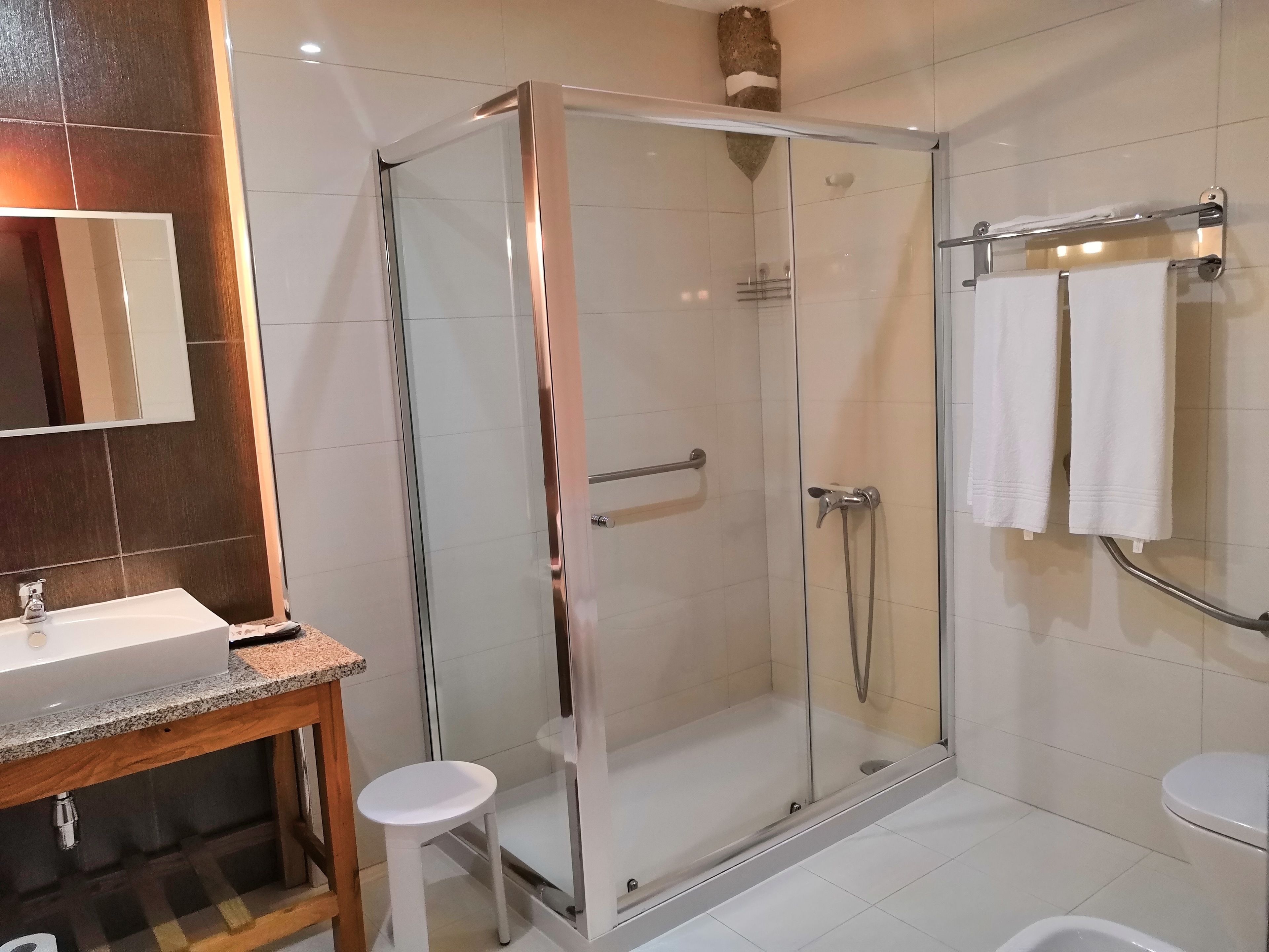 A modern bathroom with a glass-enclosed shower, a white sink, and a toilet.