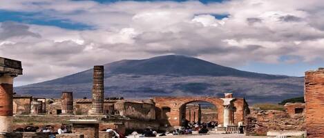 An ancient ruin with columns and arches, a clear sky, and a mountain in the background.