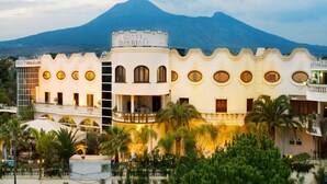 A hotel with a central tower labeled "HOTEL IMPERIAL," featuring balconies and a courtyard with palm trees. - Hotel Imperiale (Terzigno)