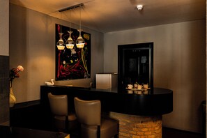 A modern bar area with a stone column, two chairs, a large abstract painting, and pendant lighting. - Hotel de Elderschans (Aardenburg)