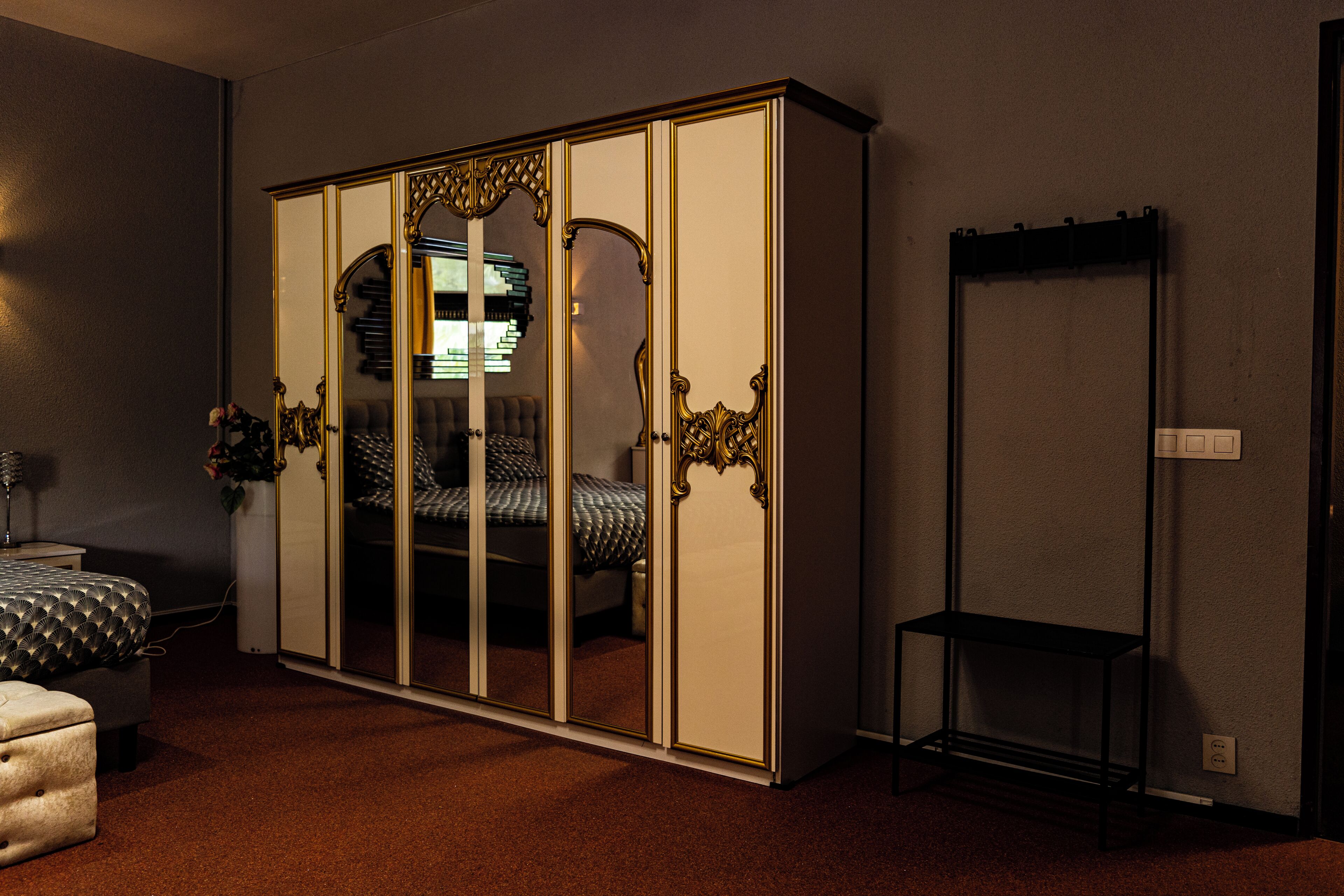 A bedroom with a wardrobe, a bed, a bedside table, and a small table.