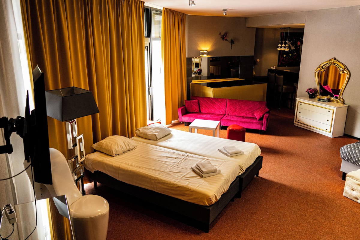 Una habitación de hotel con cama, sofá, escritorio, espejo y silla.