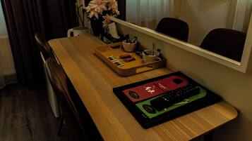 Hotelkamer met een houten bureau, een dienblad met diverse spullen, een vaas met bloemen en een spiegel die de kamer weerspiegelt.