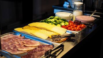 Een buffet met diverse soorten eten, zoals vleeswaren, kazen, groenten en dipsauzen.