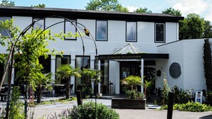 A hotel with a white exterior, a covered outdoor seating area, and a sign indicating it is a restaurant. - Hotel de Elderschans (Aardenburg)