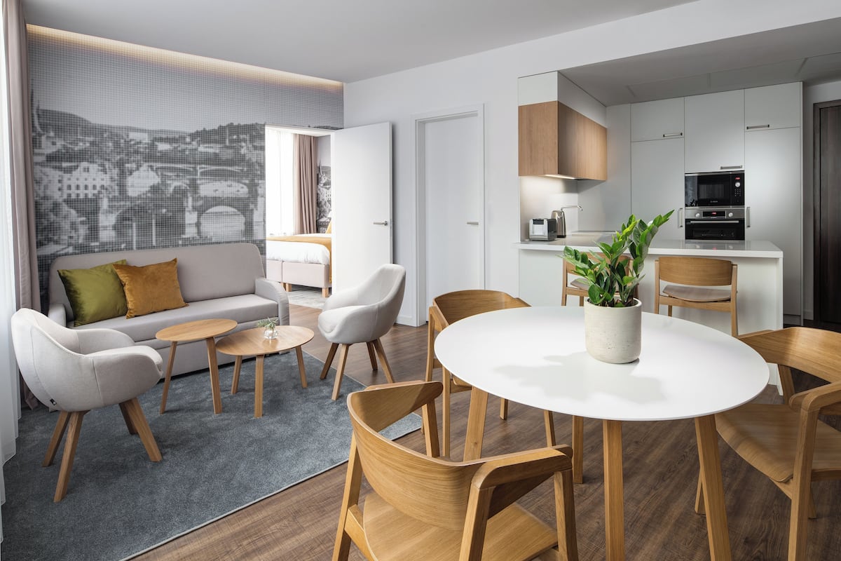 Een moderne woonkamer met een bank, stoelen, een salontafel en een eethoek met een tafel en stoelen.