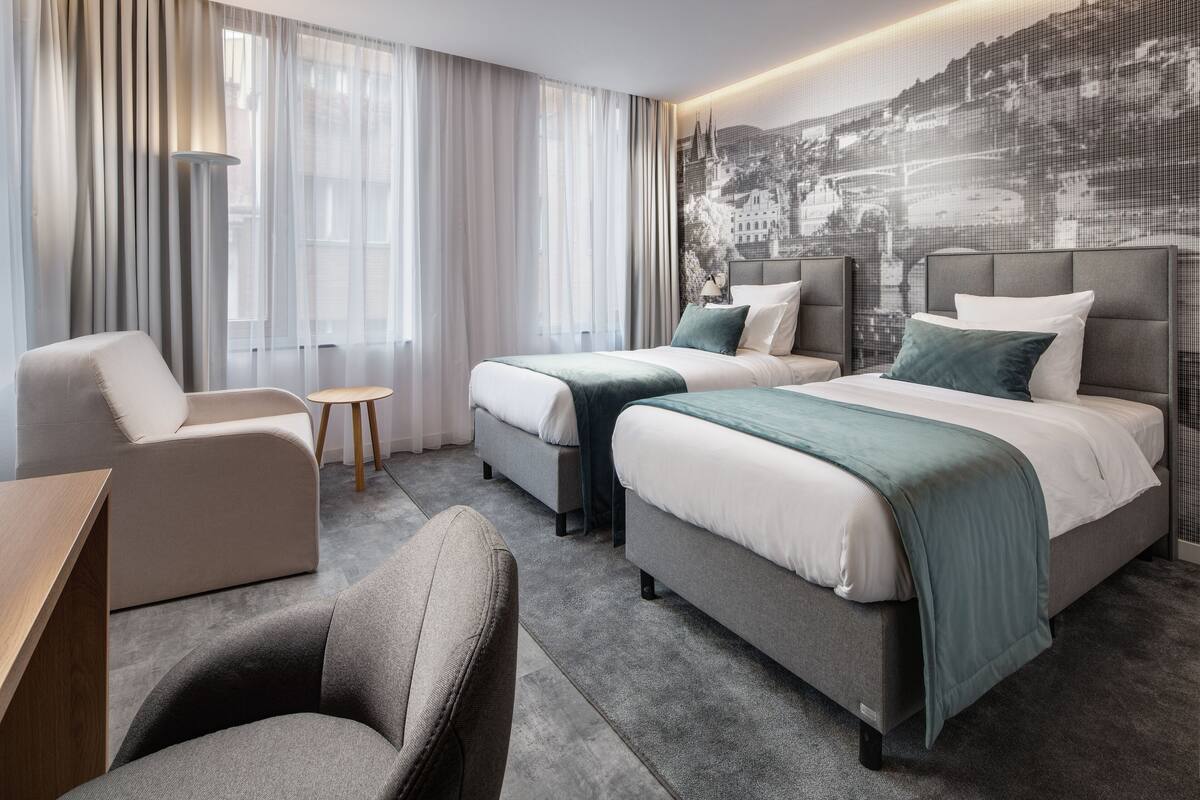 Een hotelkamer met twee bedden, een bank, een stoel en een bureau.