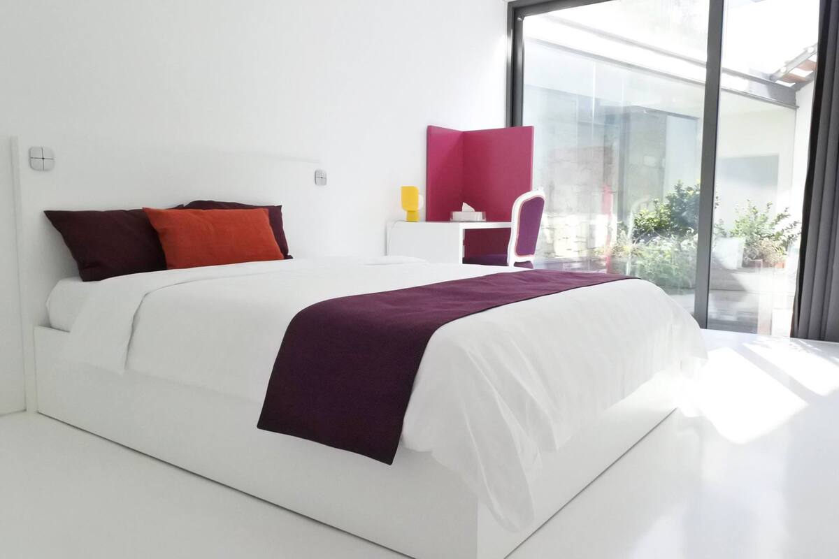 A modern bedroom with a large bed, a desk, and a chair.