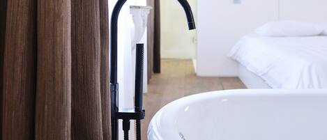 A modern bathroom with a bathtub, wooden flooring, and a white sink.