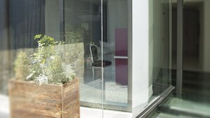 A modern interior with a glass partition, a wooden planter with plants, and a chair. - Lokàl Boutique Hotel (Larnaca)