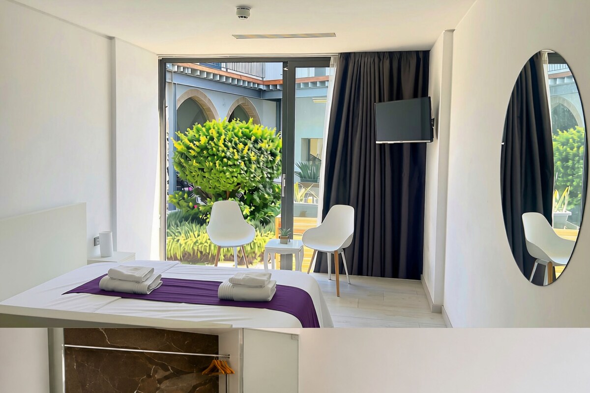 A hotel room with a bed, a desk, a TV, and a view of the outdoors.