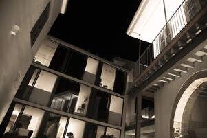 Un edificio de varios niveles con balcones y escaleras, que presenta arquitectura moderna e iluminación interior.