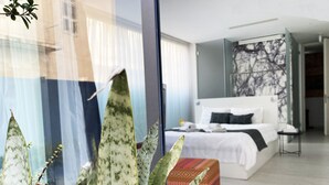 A modern hotel room with a large bed, a bedside table, and a window with sheer curtains. - Lokàl Boutique Hotel (Larnaca)