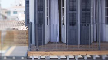 Un modelo de un edificio con balcón, una puerta con contraventanas y una ventana con cortinas.