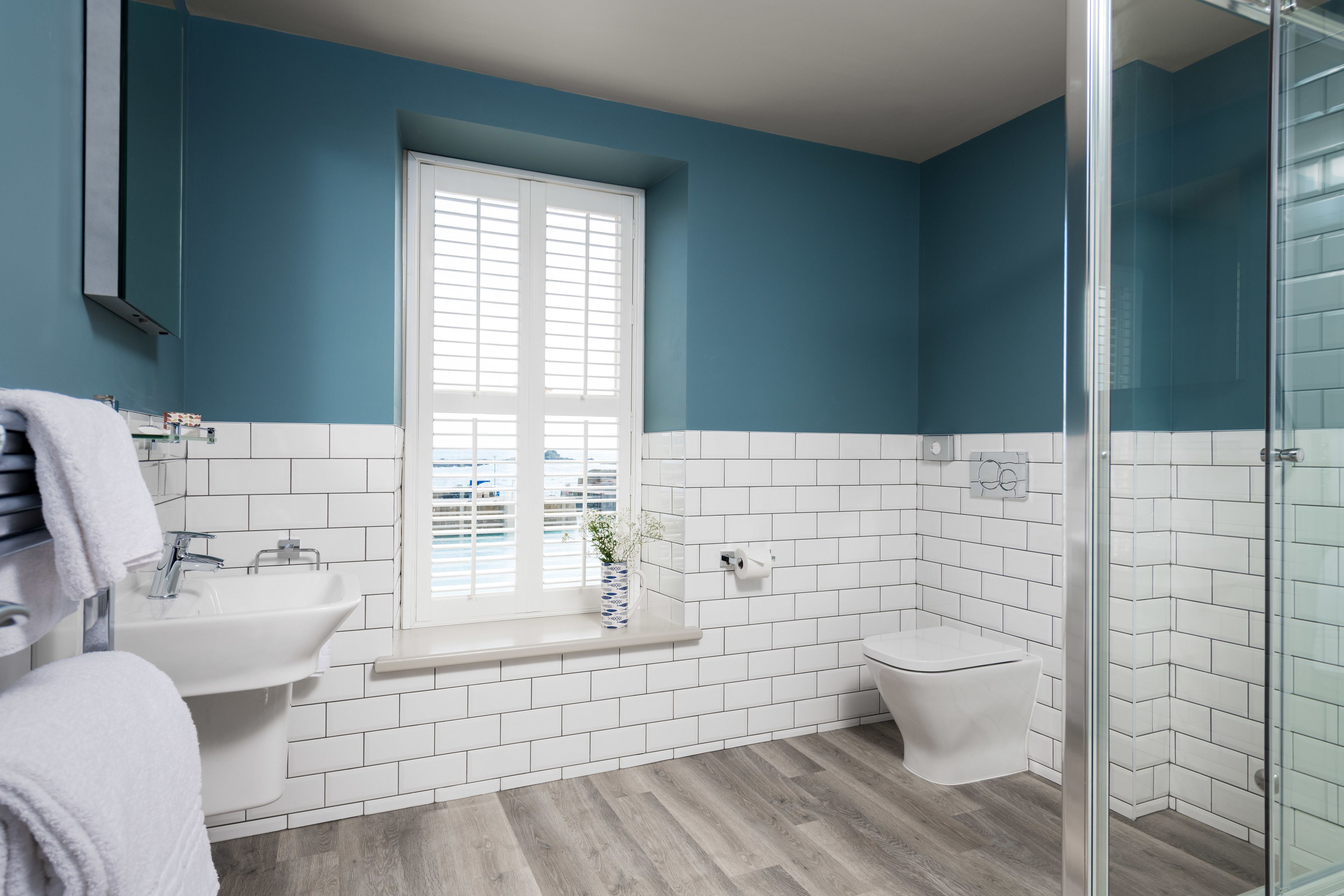 A bathroom with a window, white sink, and toilet.