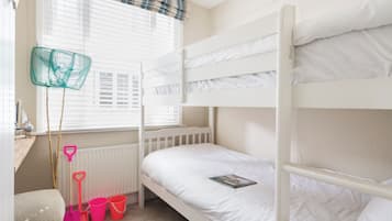 A bunk bed room with a window, a radiator, and a small shelf with a book.