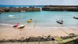 Un paysage côtier avec des bateaux ancrés près d’une digue en pierre et d’une plage de sable.