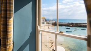 Une pièce dotée d’une grande fenêtre donnant sur un port, avec des bateaux et des bâtiments.
