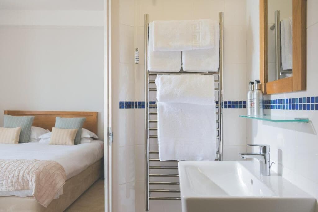 A hotel room with a bed, a bathroom with a sink and mirror, and a towel rack.