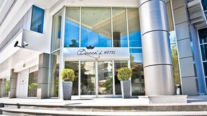 Queen's Hotel with a modern facade, large windows, and two potted plants at the entrance. - Queen's Hotel (Skopje)