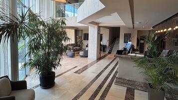 Eine geräumige Lobby mit hoher Decke, großen Fenstern und moderner Einrichtung.