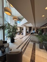 Un vestíbulo amplio con techo alto, ventanas grandes y mobiliario moderno.