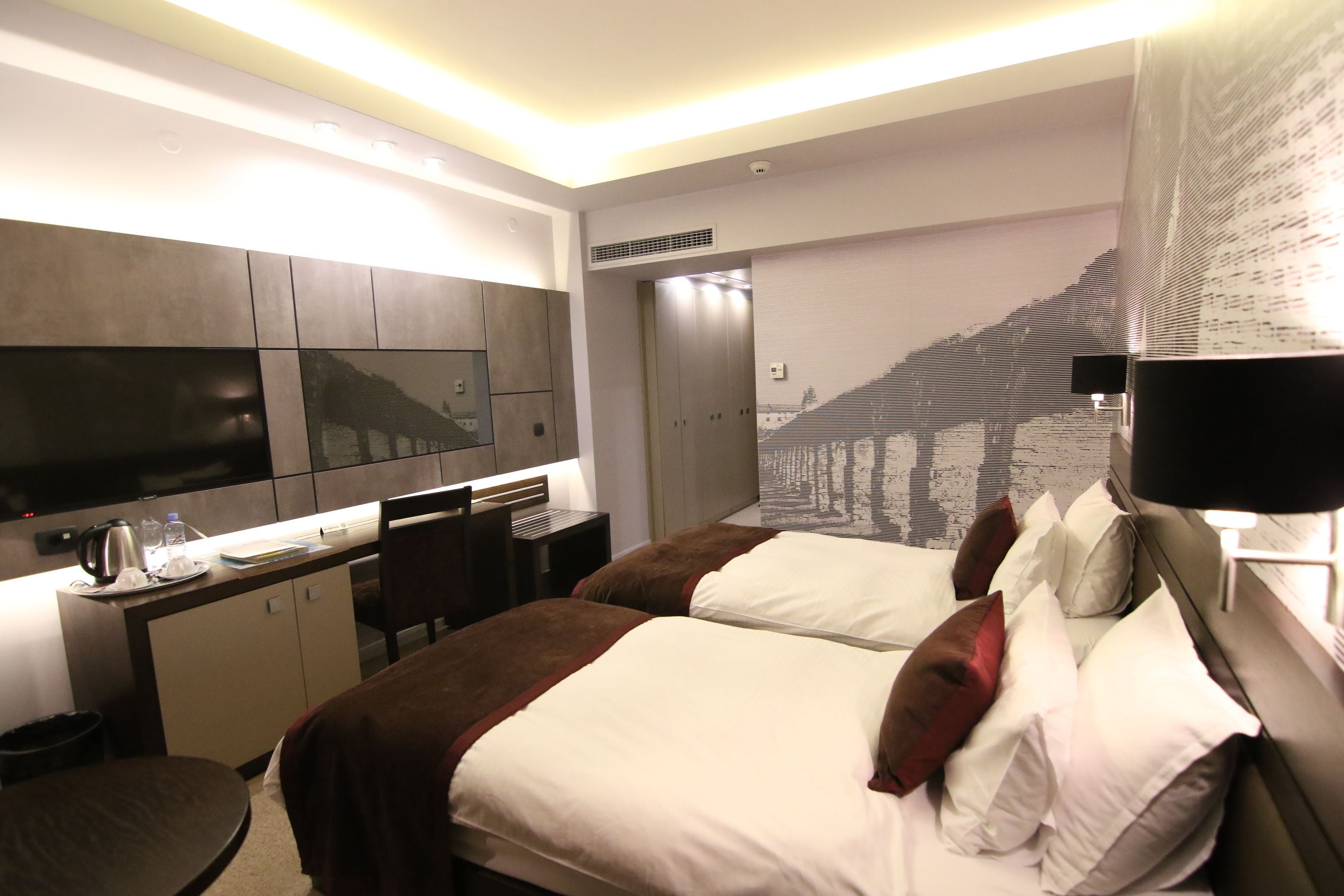 Une chambre d’hôtel équipée d’un lit, d’un bureau, d’une chaise, d’une télévision et d’une grande fenêtre.