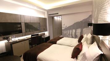 Une chambre d’hôtel équipée d’un lit, d’un bureau, d’une chaise, d’une télévision et d’une grande fenêtre.