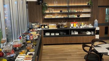 A buffet setup with various food items and a seating area with chairs.