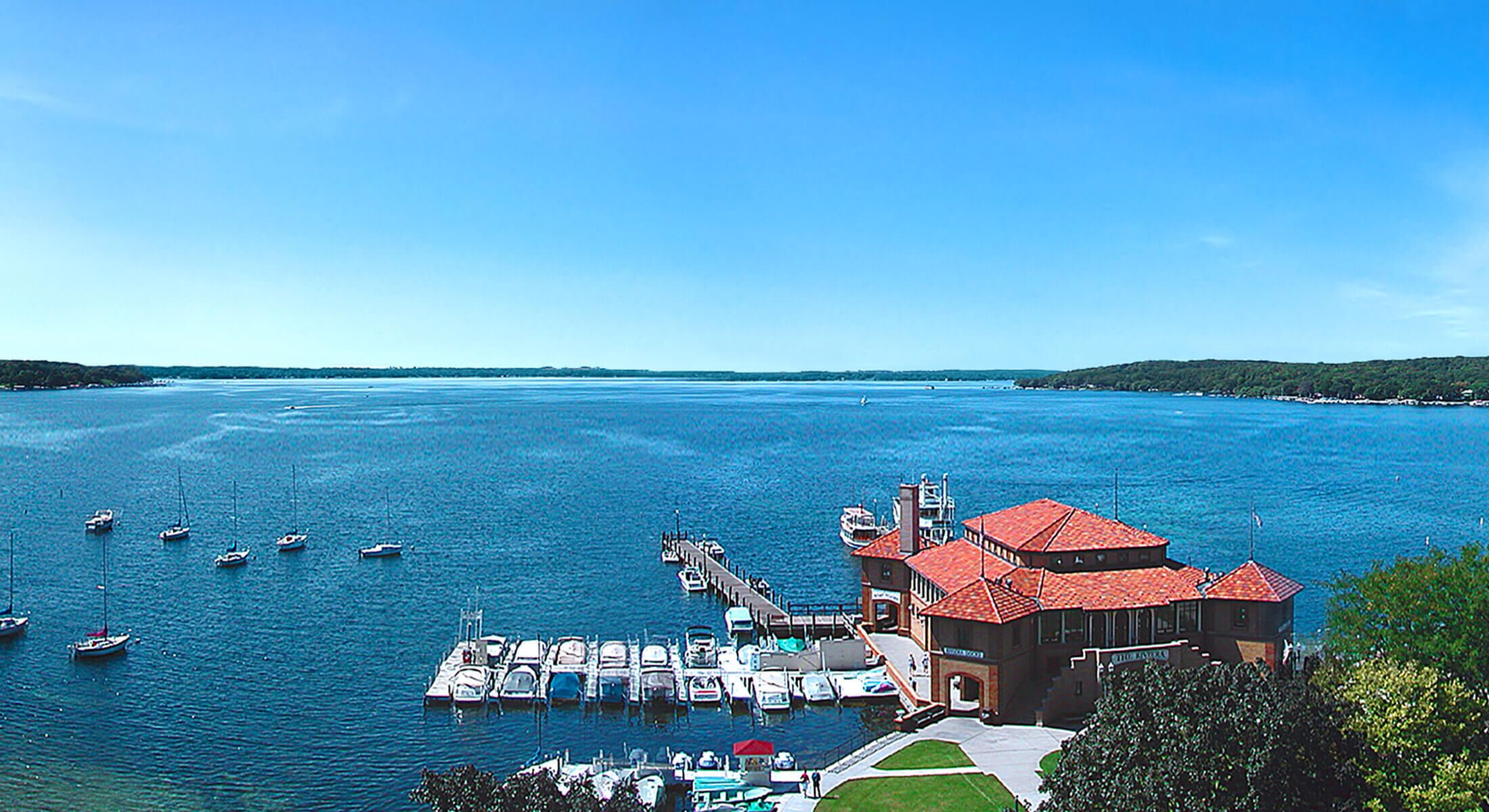 A marina with boats docked, a building with a red roof, and a clear blue sky.