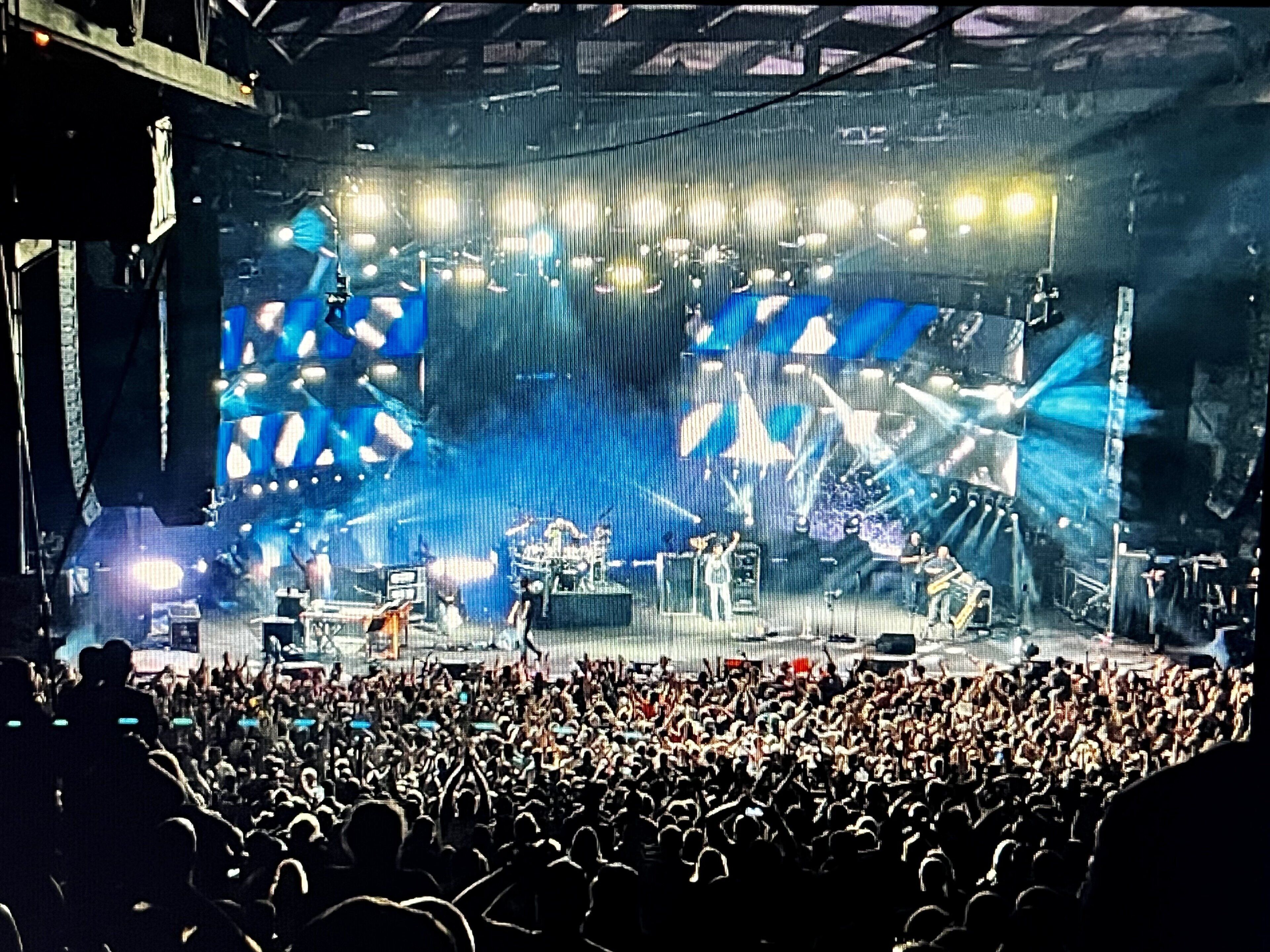 Une scène de concert avec une foule nombreuse au premier plan.