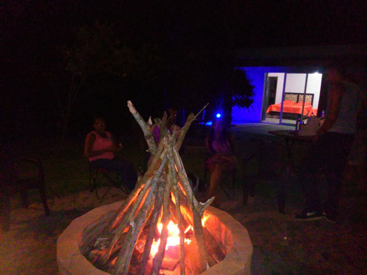 A campfire with people sitting around it at night.