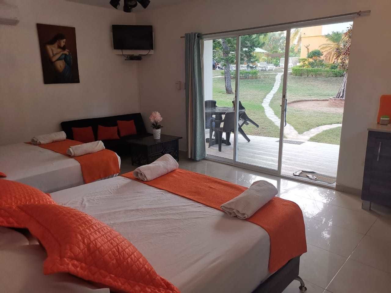 A hotel room with two beds, a TV, and a sliding glass door to a patio.