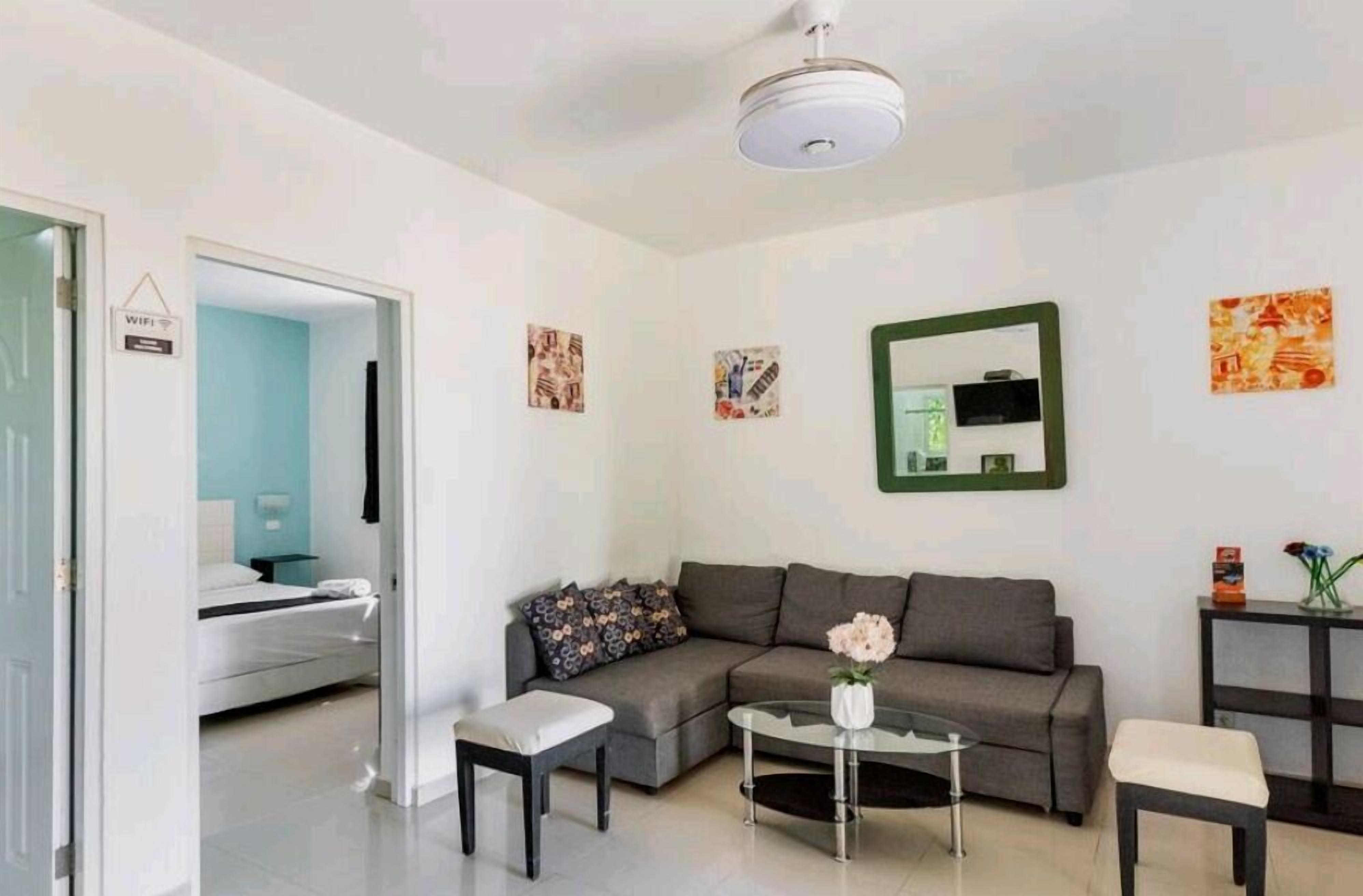 Ein modernes Wohnzimmer mit grauem Sofa, einem kleinen Couchtisch und einem an der Wand montierten Fernseher.