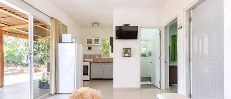 A modern interior with a kitchen, a dining area, and a living space with a TV.