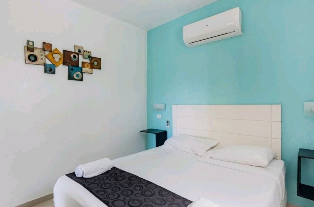 Une chambre d’hôtel comprenant un lit, un climatiseur fixé au mur et un élément décoratif mural.