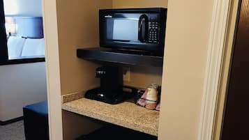 A compact kitchenette with a microwave, coffee maker, and a small refrigerator.