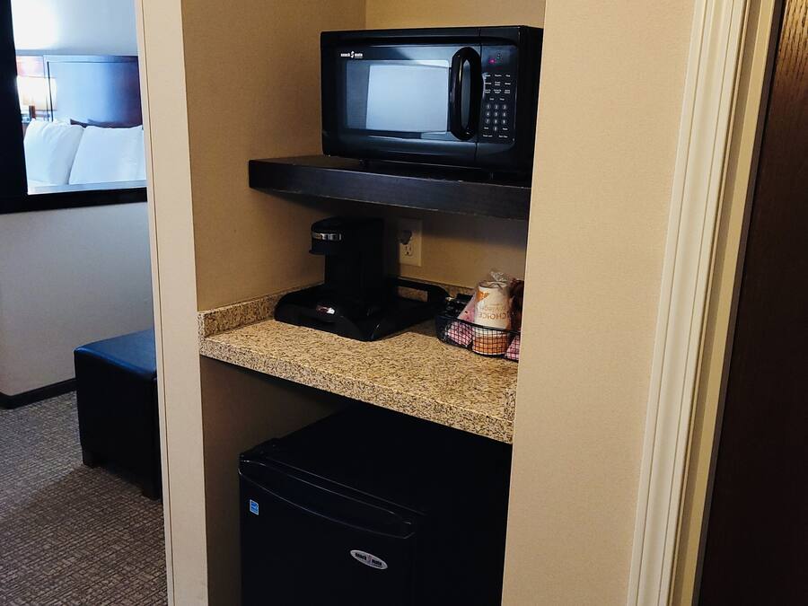 A compact kitchenette with a microwave, coffee maker, and a small refrigerator.