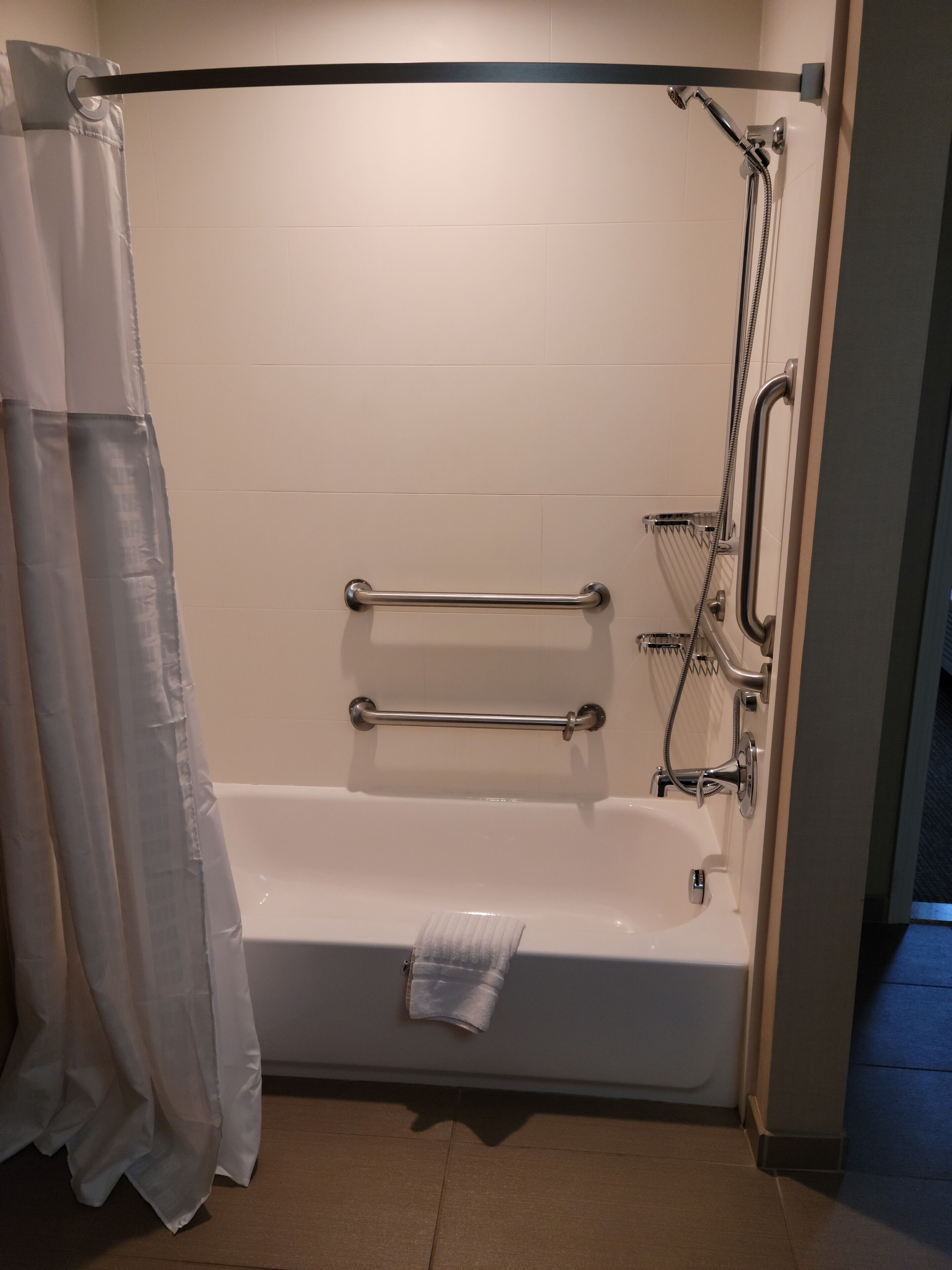 A standard bathroom with a bathtub, grab bars, and a showerhead.