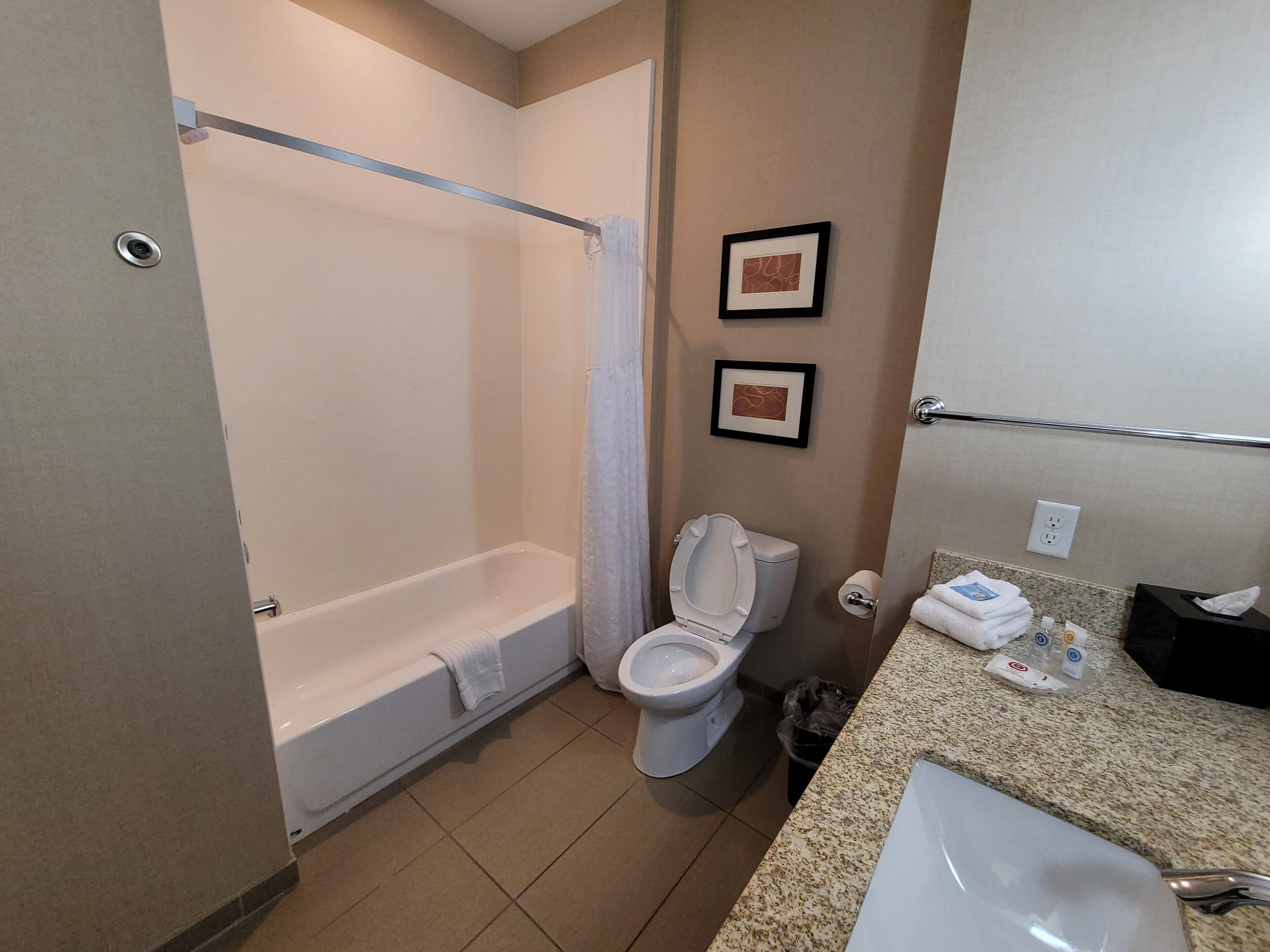 A bathroom with a bathtub, toilet, sink, and two framed pictures on the wall.
