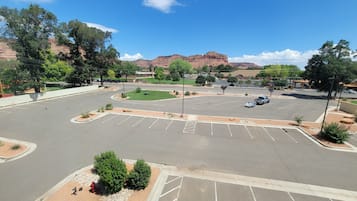 A parking lot with multiple parking spaces, a landscaped area with trees, and a view of mountains in the background.