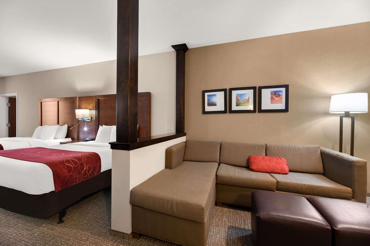 Ein Hotelzimmer mit Bett, Sofa, Stuhl und Schreibtisch. An der Wand hängen drei gerahmte Bilder.