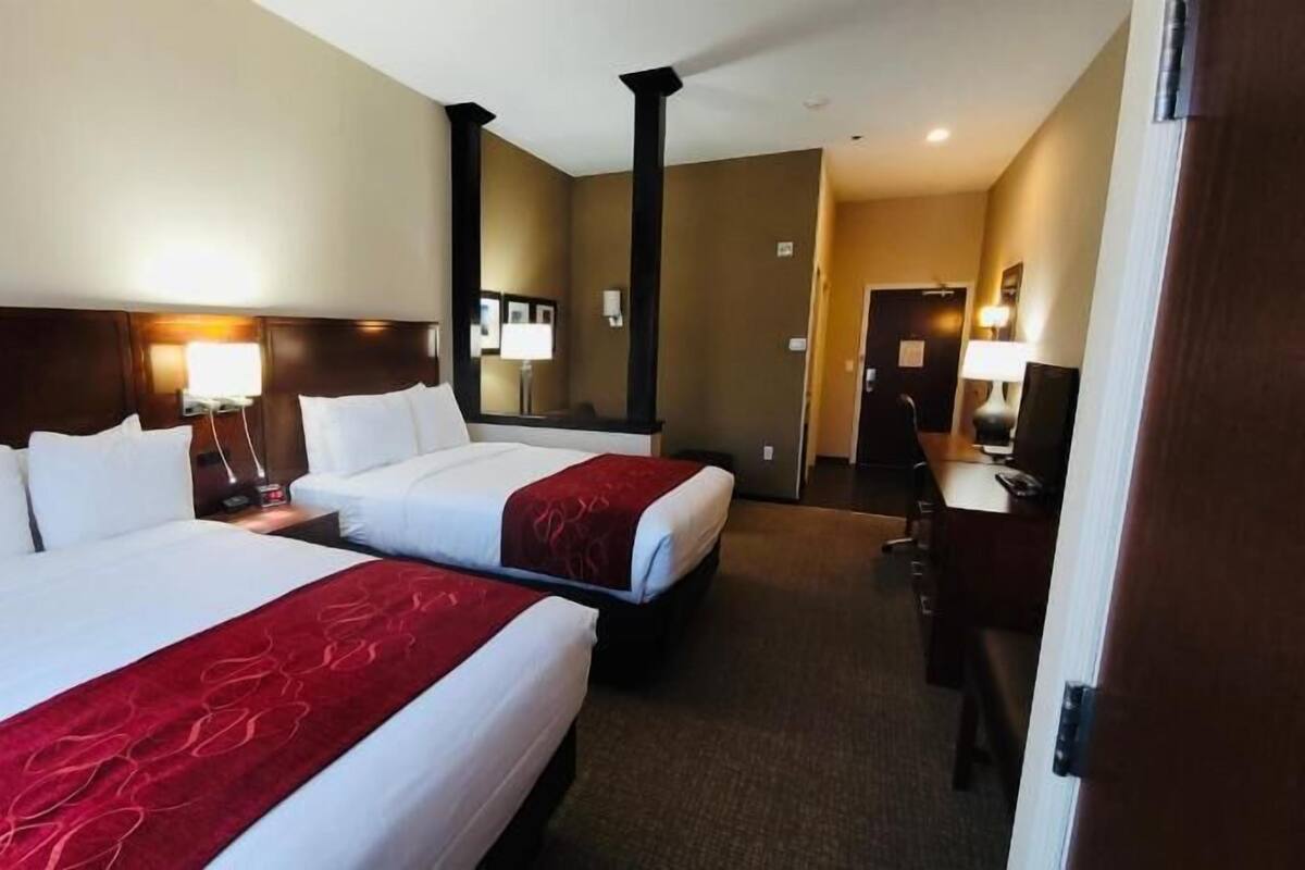 Ein Hotelzimmer mit zwei Betten, einem Schreibtisch und einem Stuhl.