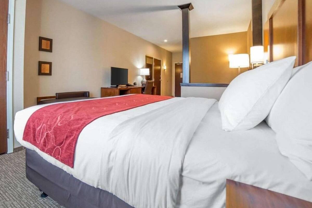Ein Hotelzimmer mit einem großen Bett, einem Schreibtisch, einem Fernseher und einem Spiegel.