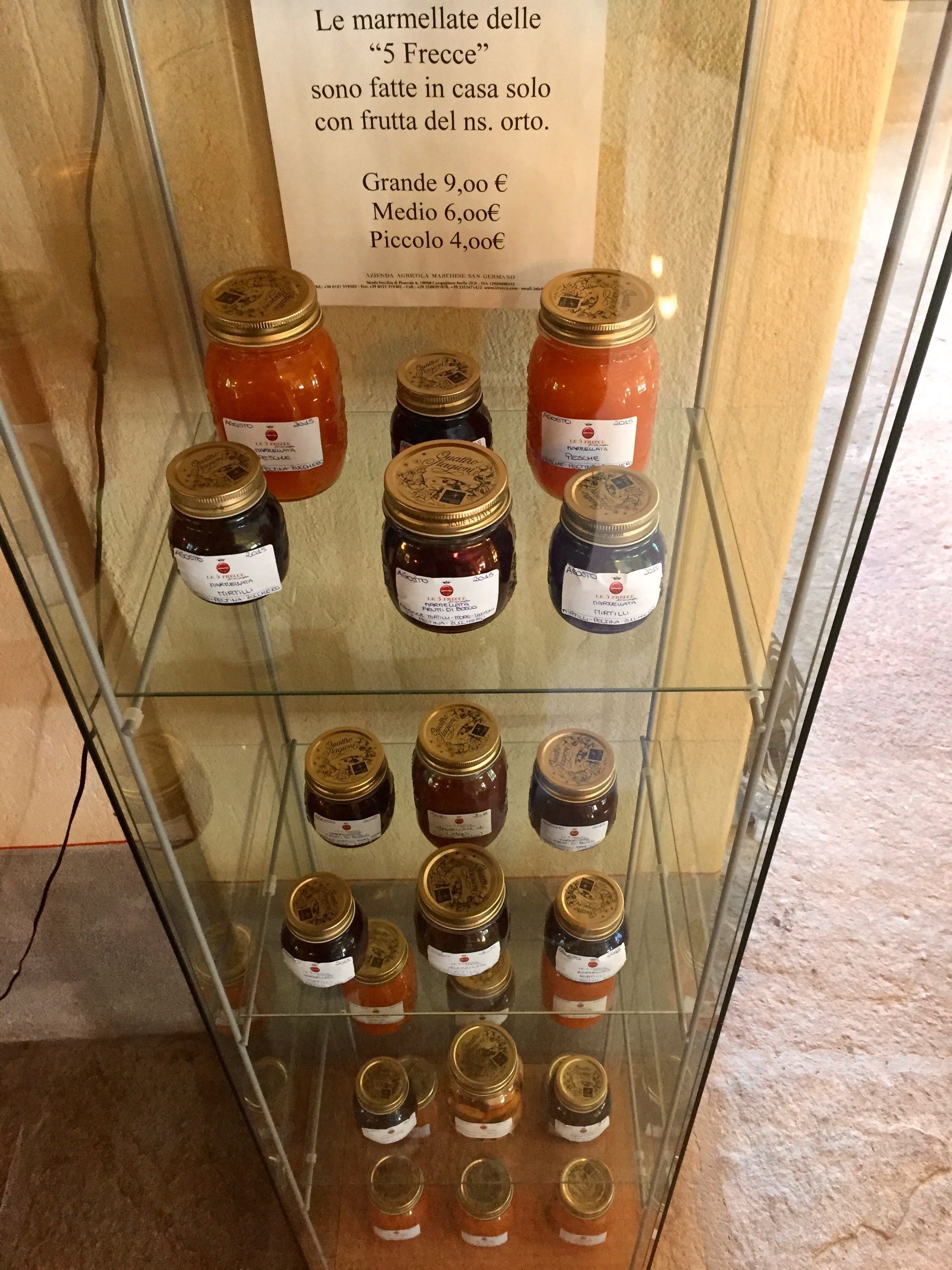 A display case with various jars of marmalade labeled with names and prices.